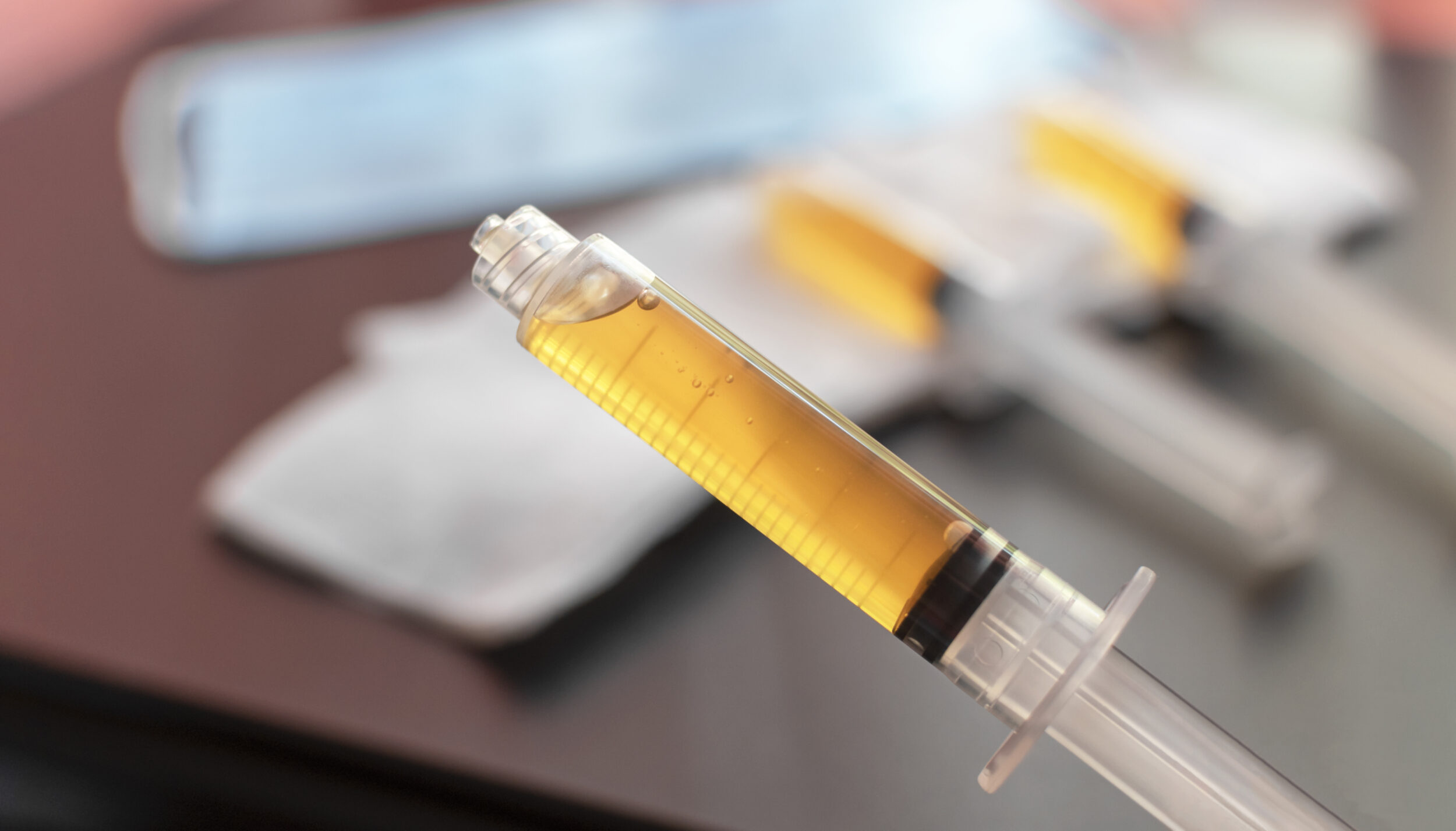 Blood plasma in a syringe on a blurred background. Blood plasma as a solution for the treatment of coronavirus.