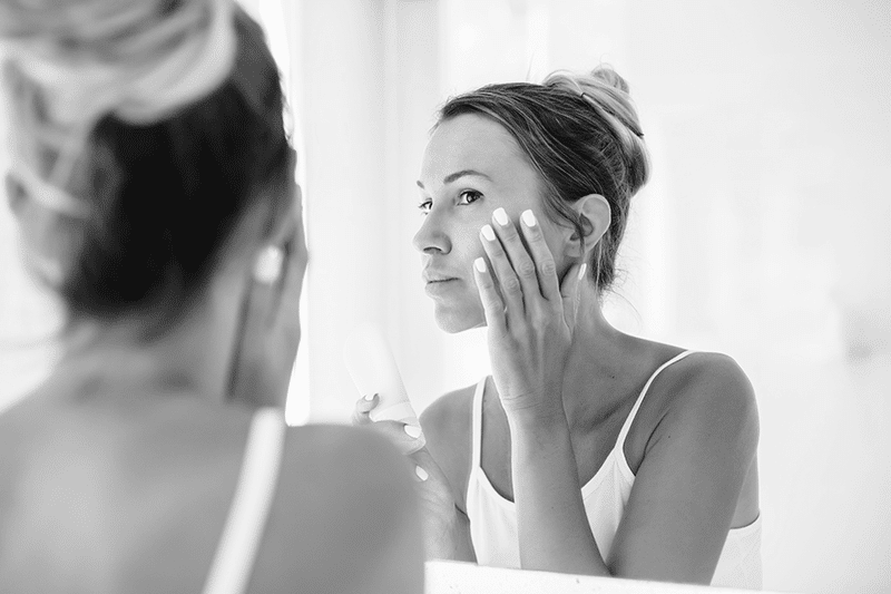 Woman Looking Face Mirror Applying Cream