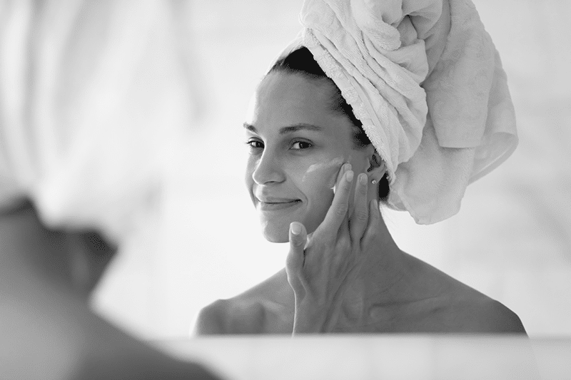 Woman Putting Cream On Face After Shower
