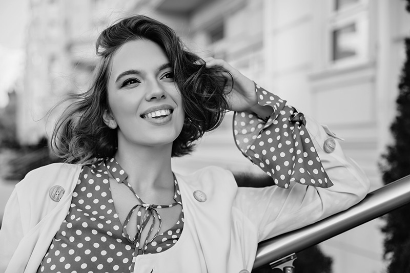 Cheerful brown haired woman in elegant outfit looking around. Outdoor portrait of sensual attractive girl with short hairstyle standing on blur city background.